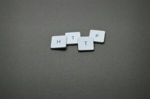 High-angle photo of keyboard tiles spelling HTTP on a dark background.